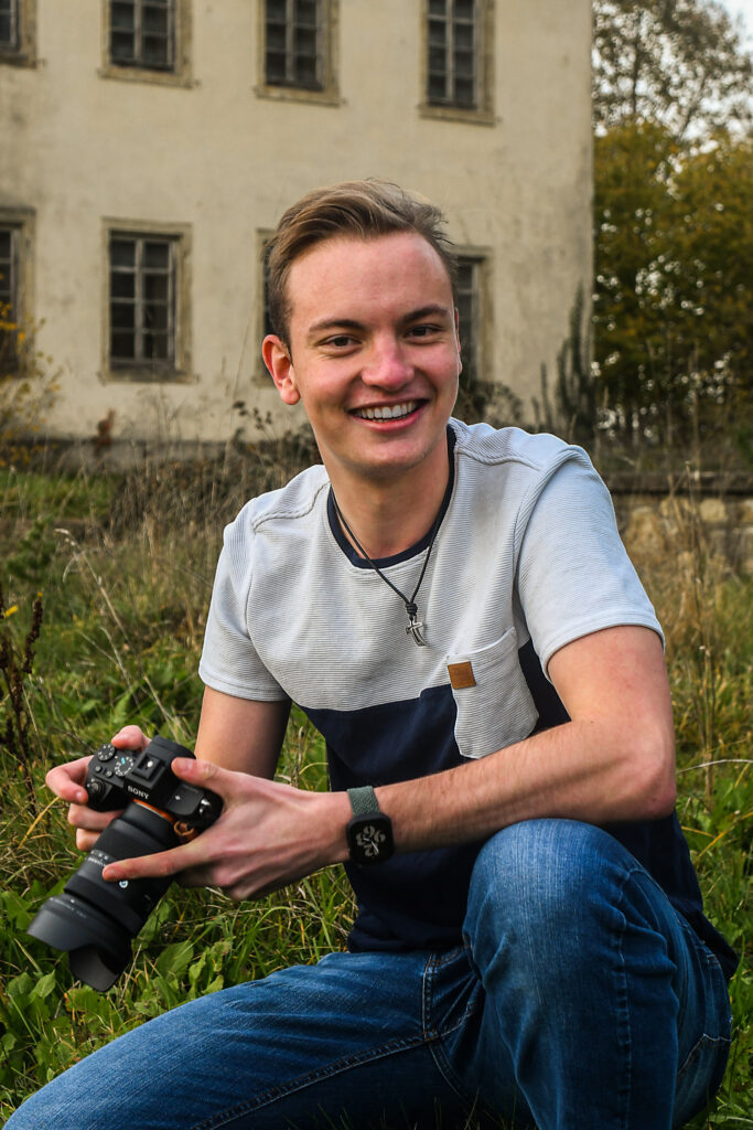 Tim Hirschmiller, Hochzeitsfotograf im Ostalbkreis, sitzt mit Kamera in der Hand